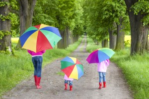 mother and her daughters with umbrellas in spring alley - Evolve Financial Services Plan Build Retire
